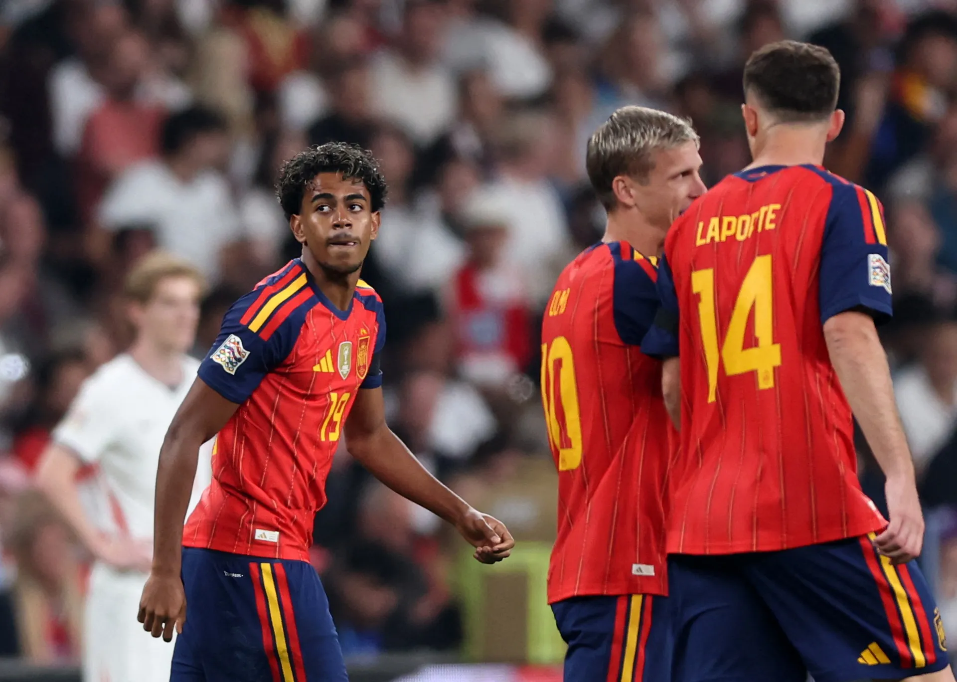 Spain players in red shirts gather on the pitch during an international football match.