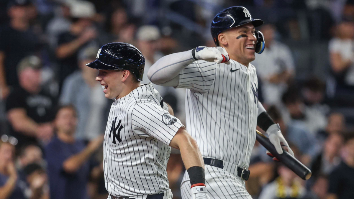 Two New York Yankees players in pinstripes celebrate together during a game