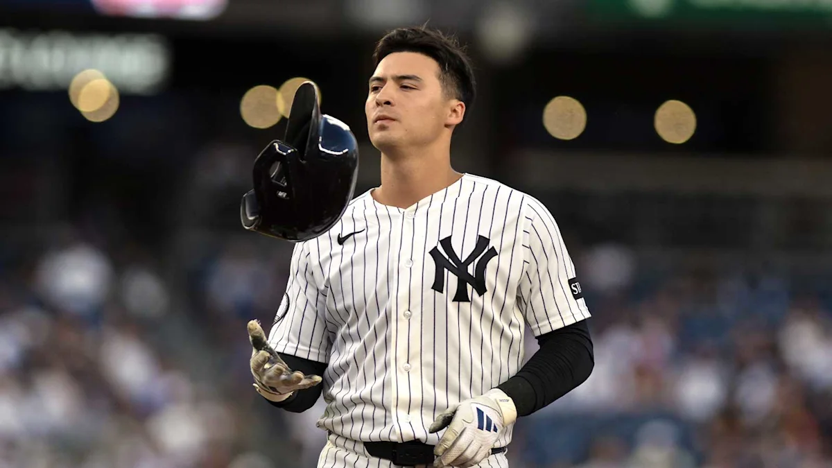 Yankees baseball player holding a helmet while standing on the field in pinstriped uniform