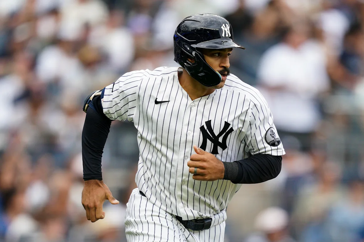 New York Yankees player in pinstriped uniform and batting helmet running on the field.