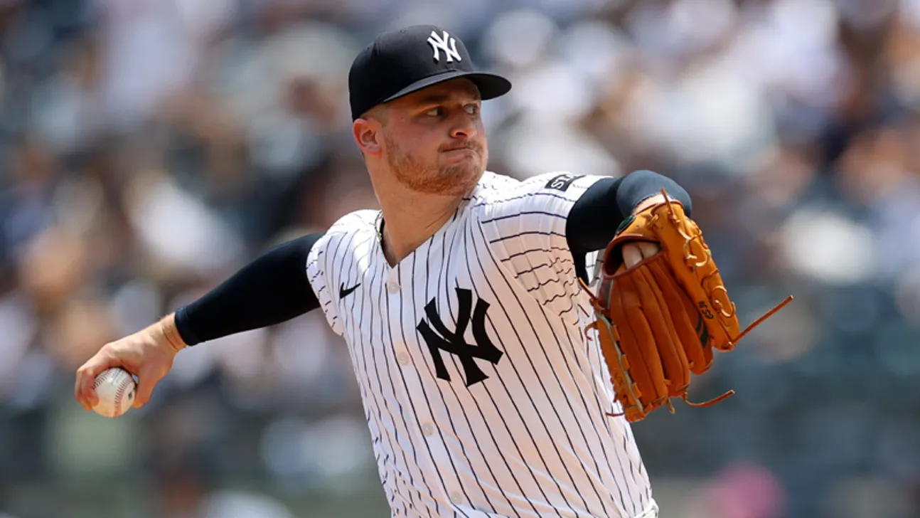 Yankees pitcher in pinstripes and cap throws a baseball with glove raised.