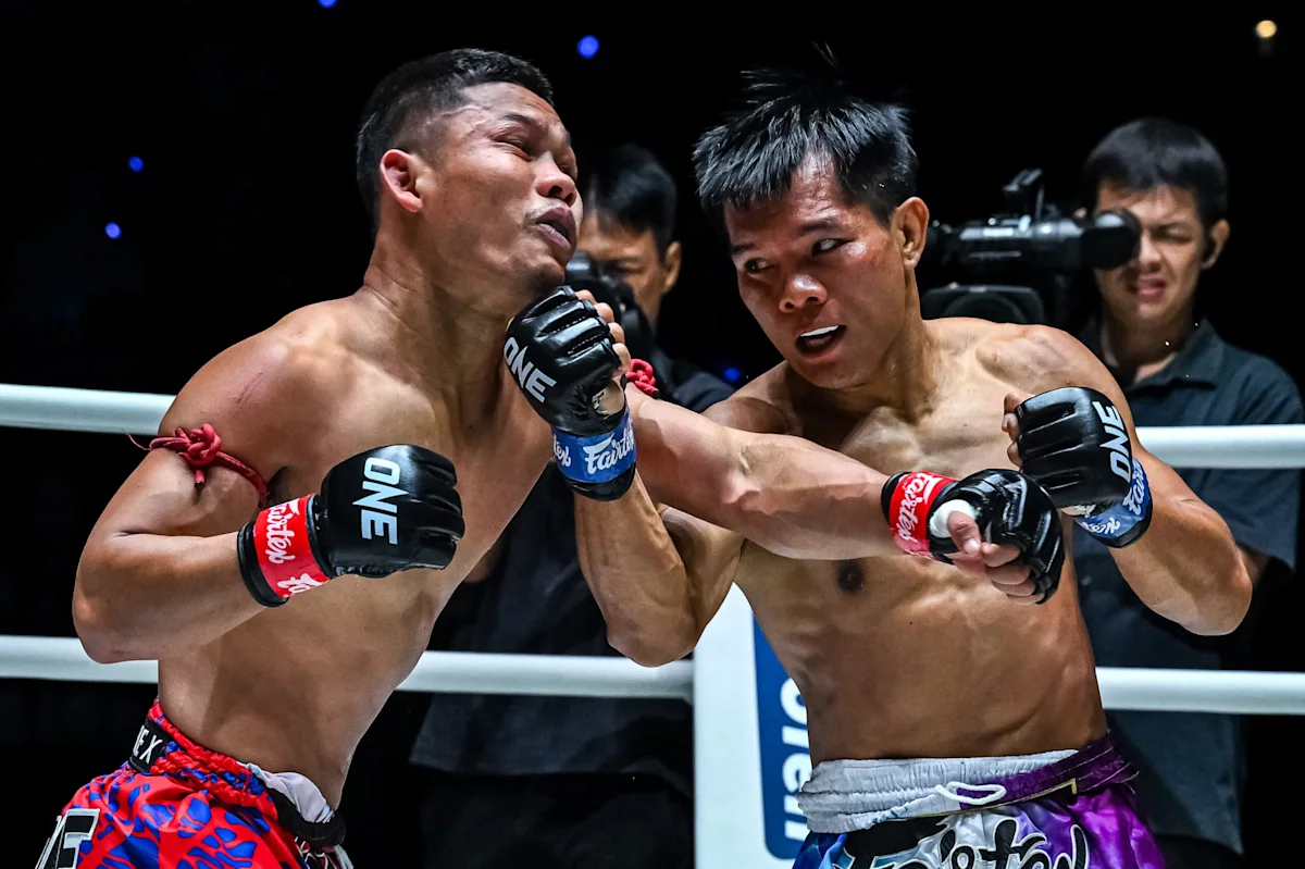 Two Muay Thai fighters exchange punches inside a ring during a closely contested bout.