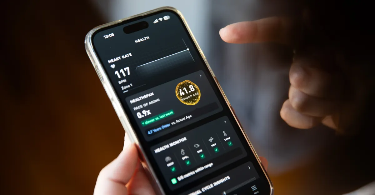 Hand holding smartphone displaying health metrics, including heart rate and a health age score.