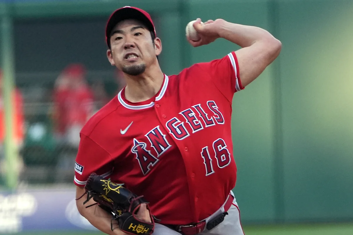 Baseball pitcher in a red Angels jersey winds up to throw during a game.