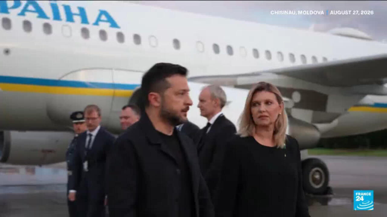 Man and woman walk past a Ukrainian-marked aircraft on an airport tarmac.