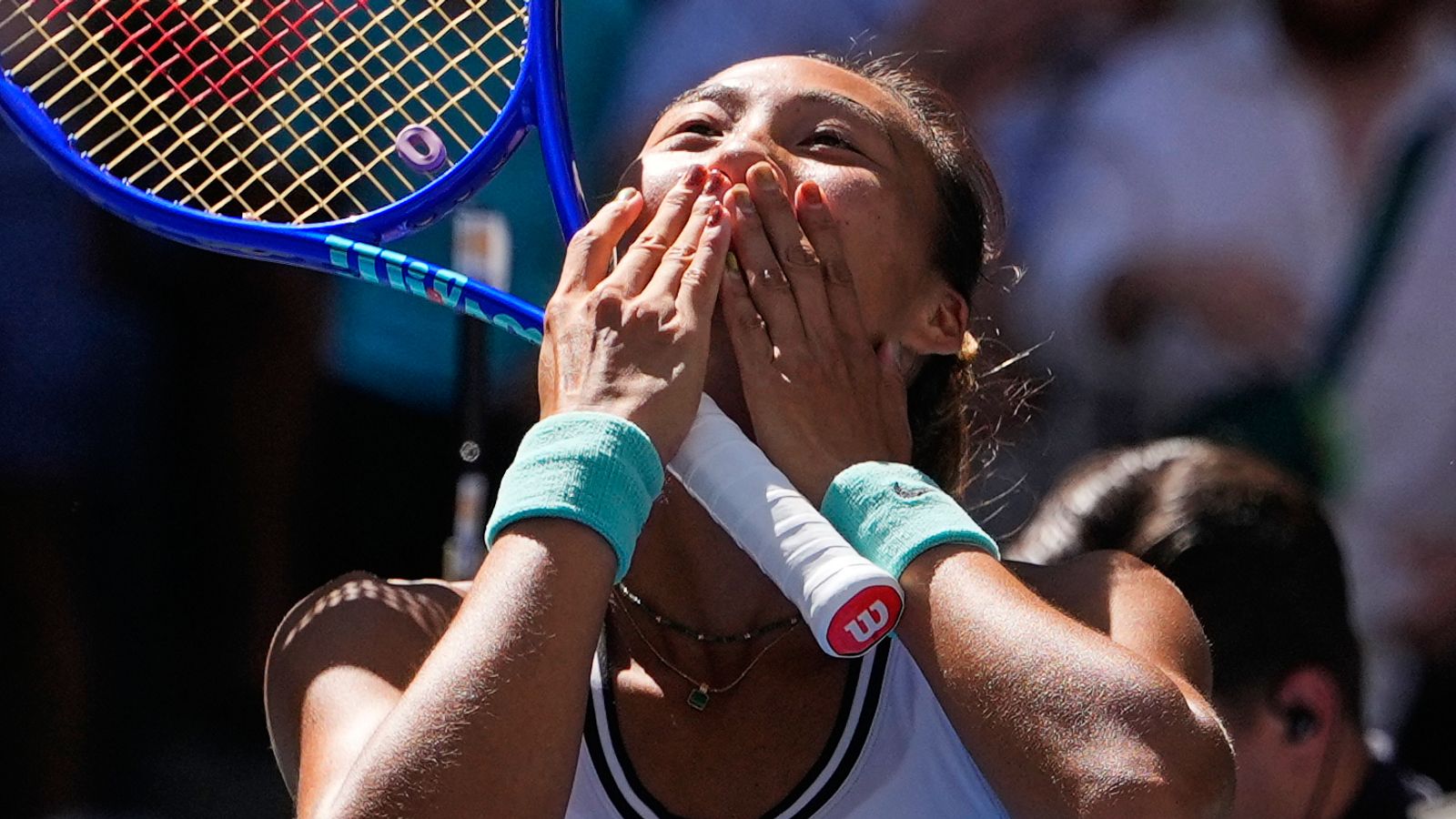 Tennis player blows a kiss while holding a racket during a match