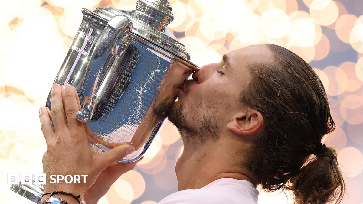 Tennis player with tied-back hair kisses a large silver championship trophy