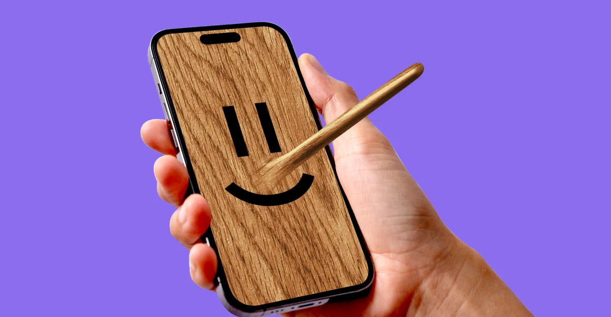 A hand holds a smartphone displaying a smiling face on a wood-textured screen against a purple background.