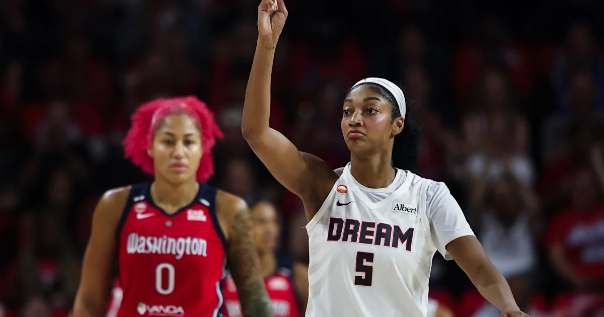 A Dream player raises one arm as a Mystics player stands behind her on court.