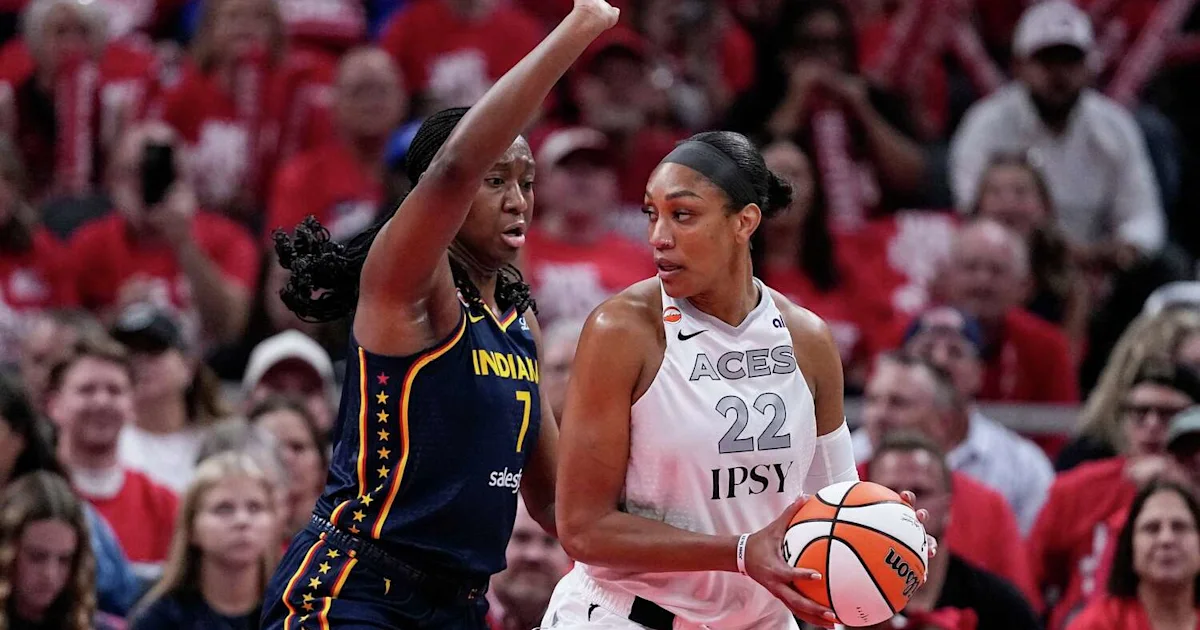 Indiana player raises an arm beside an Aces player holding the basketball during a game.