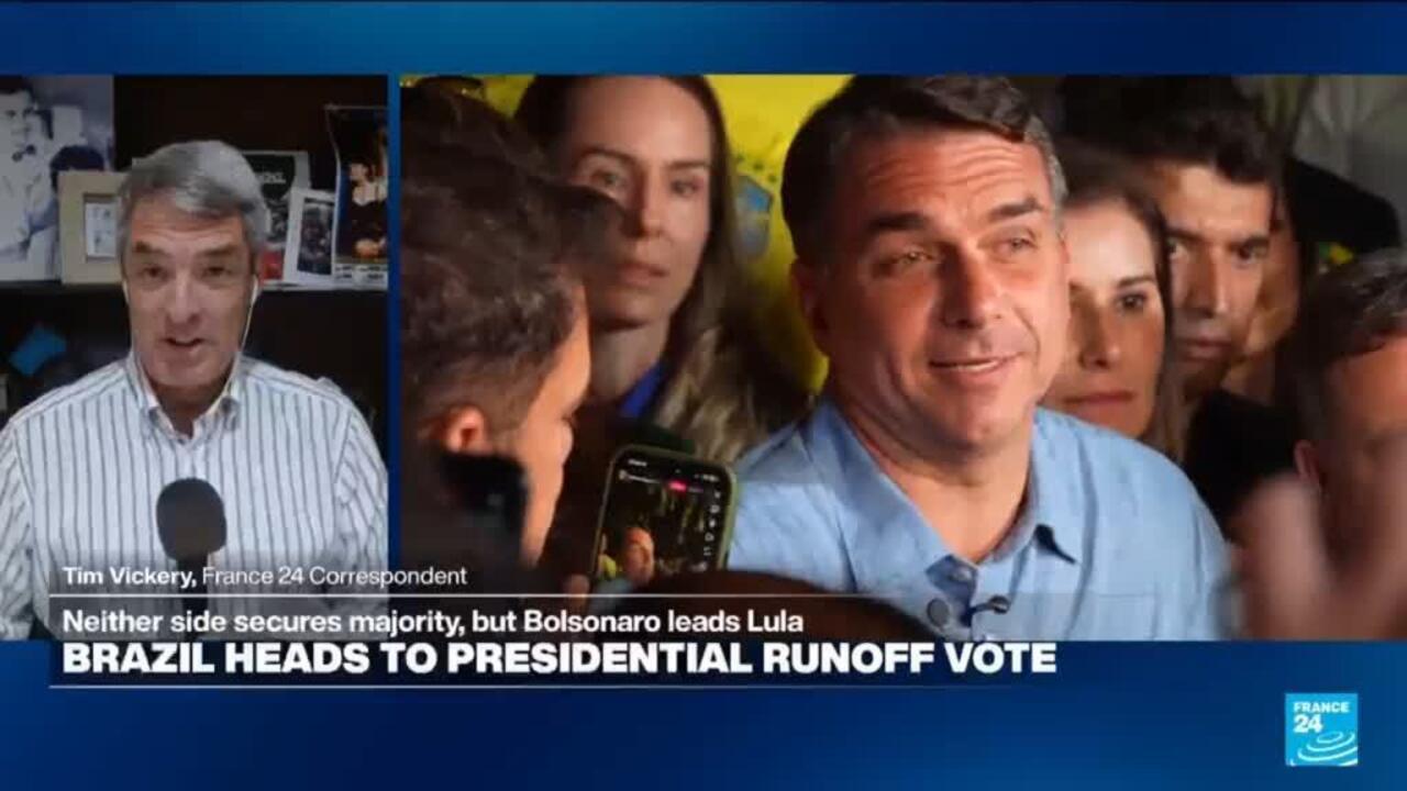 Split-screen shows a correspondent speaking beside a candidate surrounded by reporters and cameras.