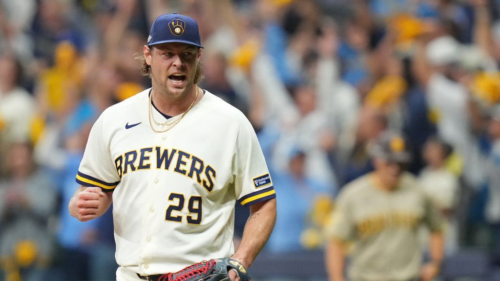 Milwaukee Brewers pitcher wearing number 29 walks across the field as a blurred player stands behind him.