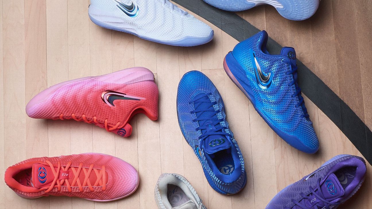 Colorful basketball shoes in white, pink, blue, and purple arranged on a wooden floor.