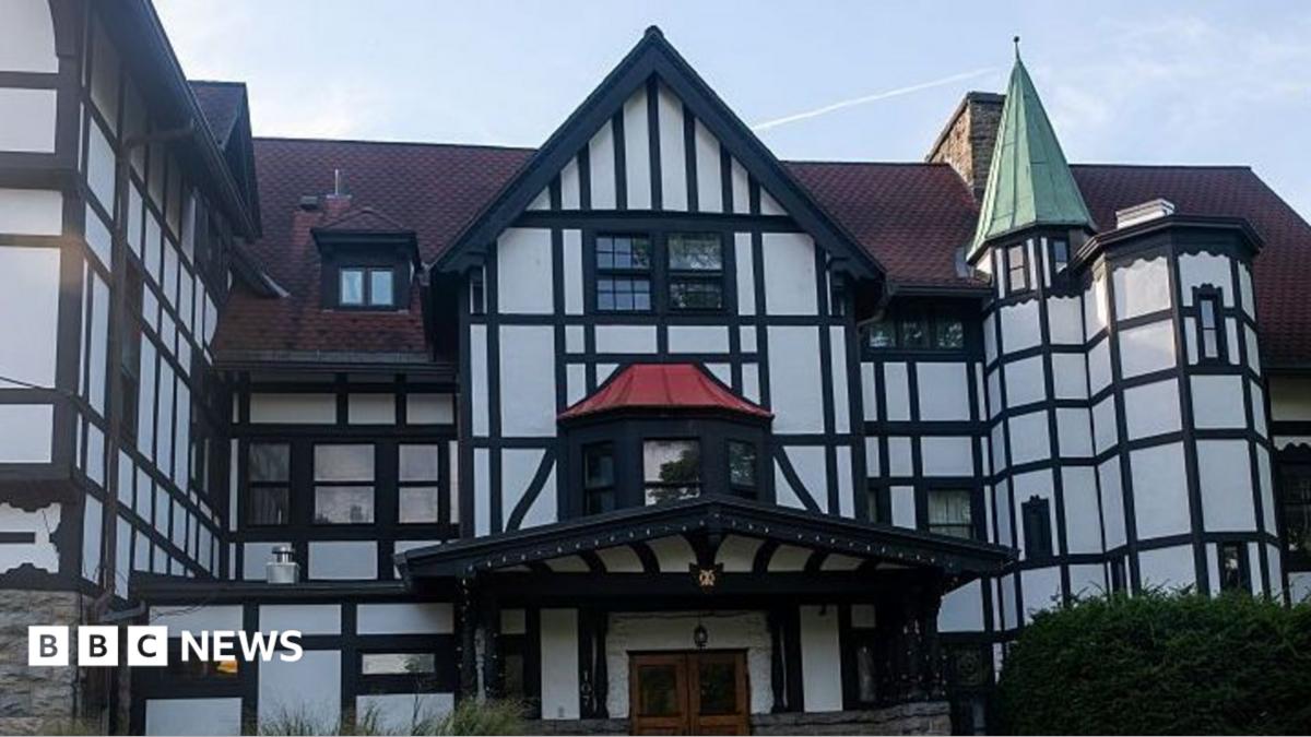 Black-and-white half-timbered building with steep red roofs, a green turret, and BBC News watermark.