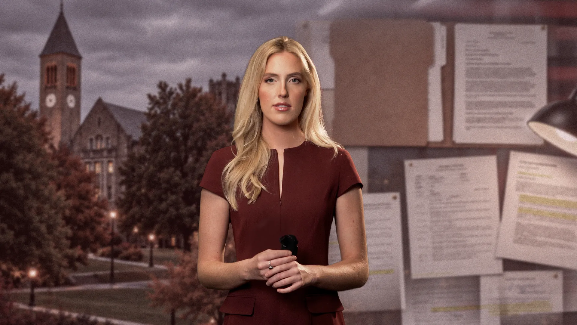 A blonde woman holds a microphone in front of a campus building and a bulletin board covered with papers.