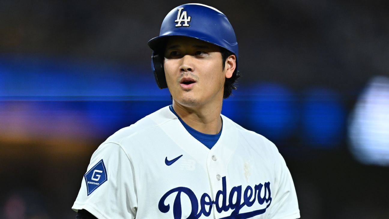 Baseball player in a blue batting helmet and white Dodgers jersey looks to the side.