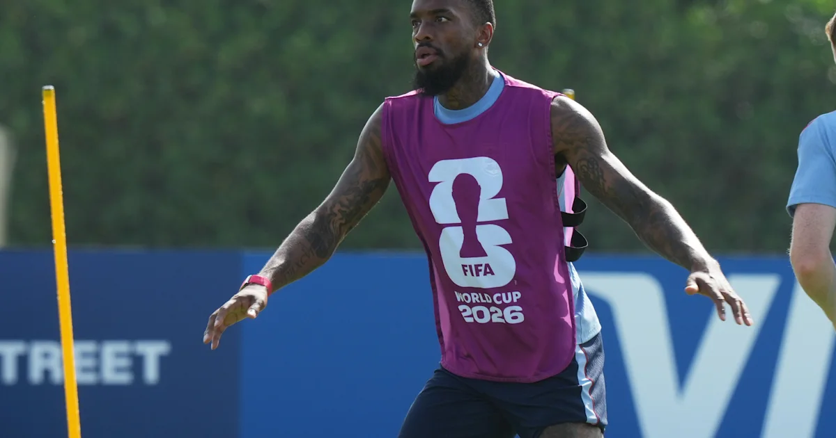 A footballer in a purple FIFA World Cup 2026 training bib runs across a field during practice.