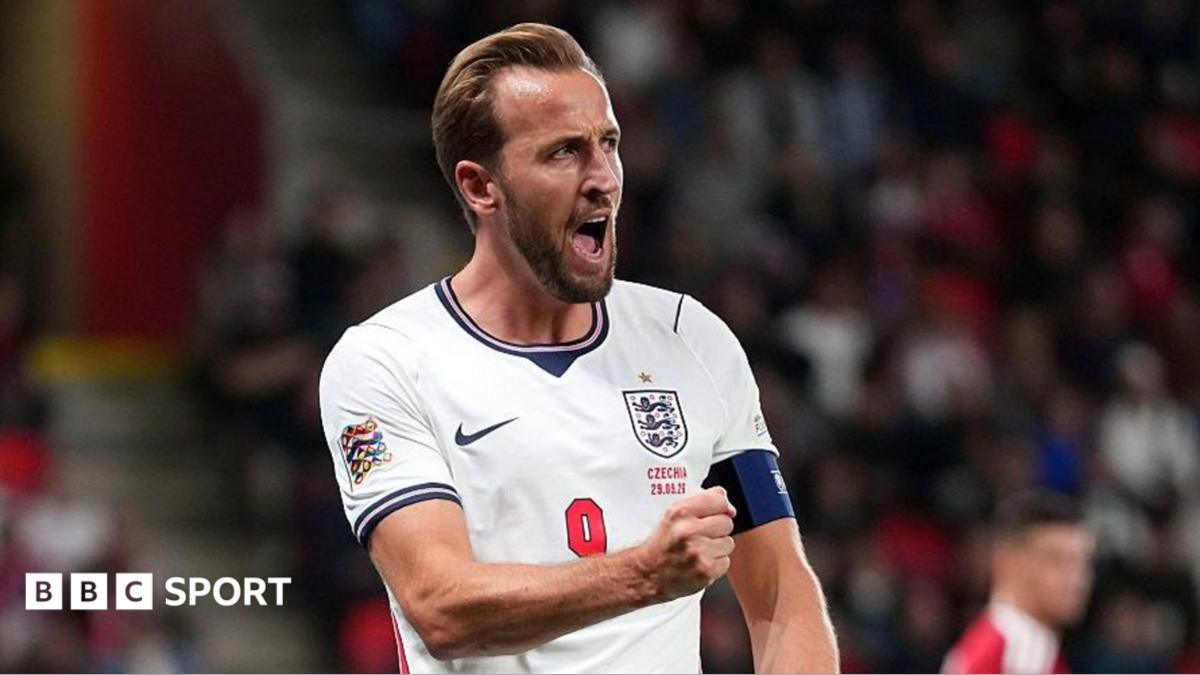 England player in a white number nine shirt shouts with a fist clenched during a match.