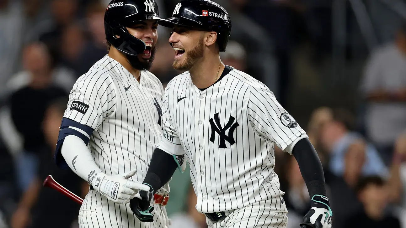 Two New York Yankees players in pinstriped uniforms celebrate together on the field.