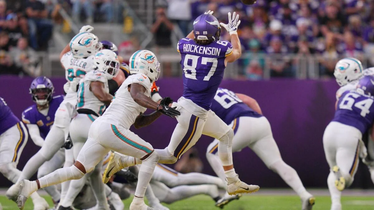 Vikings tight end catches a football as Dolphins defenders close in during a game.
