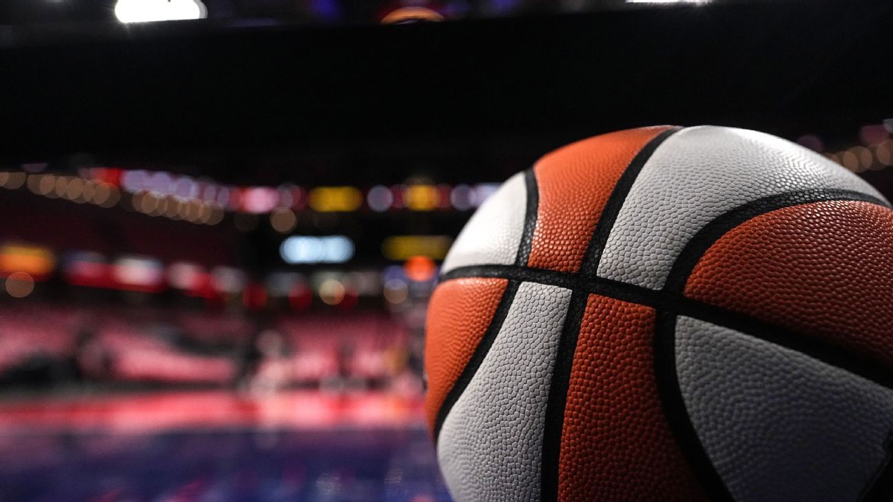 Close-up of an orange and white basketball with a blurred indoor court in the background.