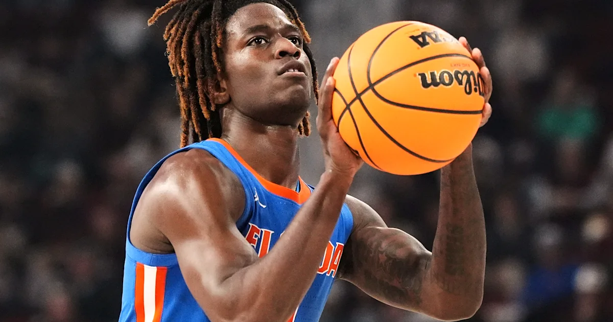 Basketball player in a blue and orange jersey holds a ball in shooting position.