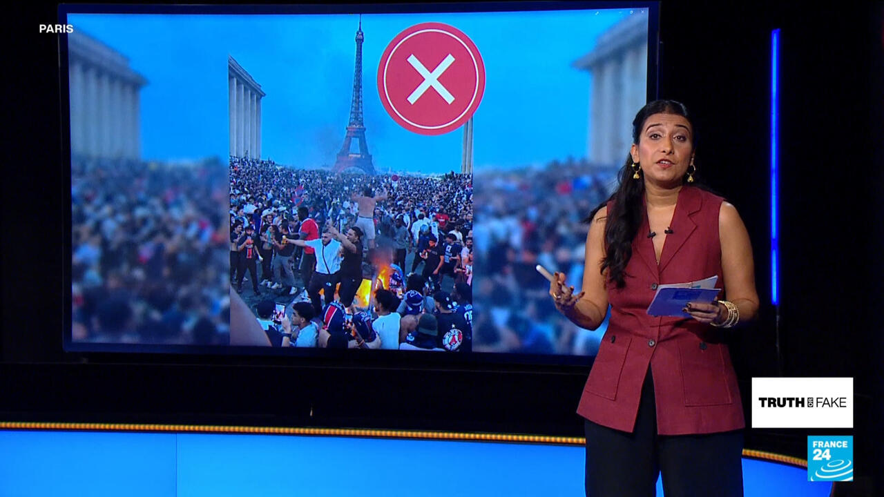 News presenter stands beside a screen showing a crowded Paris street scene and a red crossed-circle symbol.