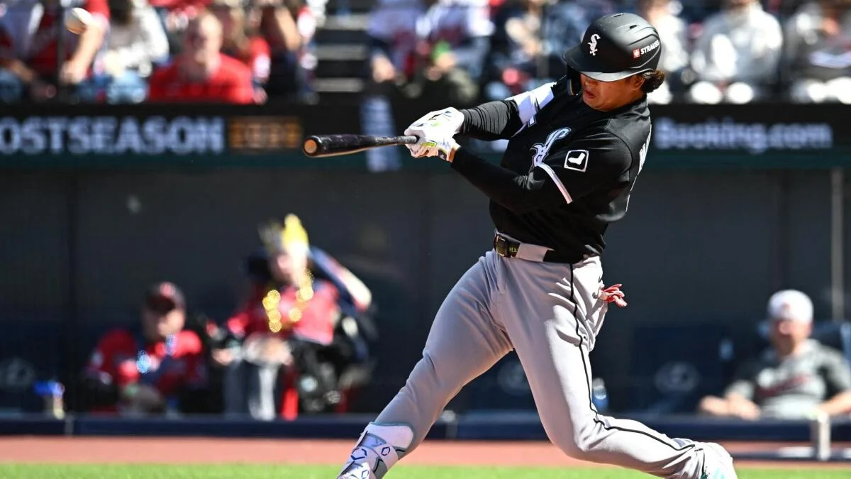 A White Sox batter swings at a pitch during a sunlit baseball game.
