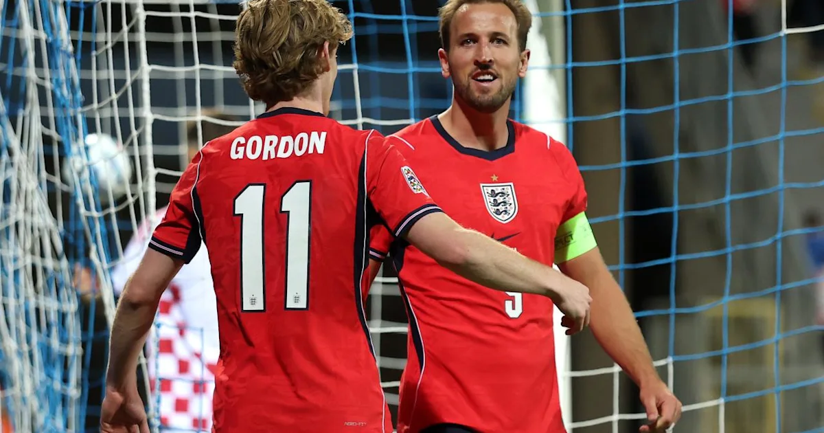 Two England players in red shirts celebrate in front of a goal net.
