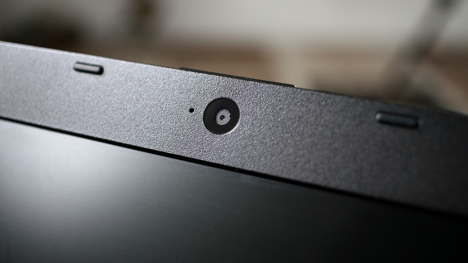 Close-up of a laptop webcam and small indicator on the upper edge of its dark screen.
