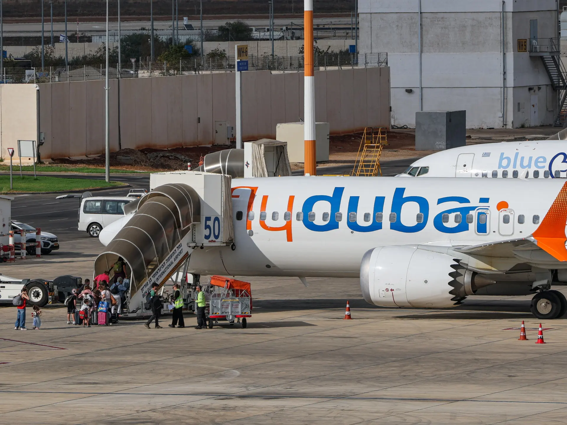 Passengers board a Flydubai aircraft from an airport stairway as ground crew stand nearby.