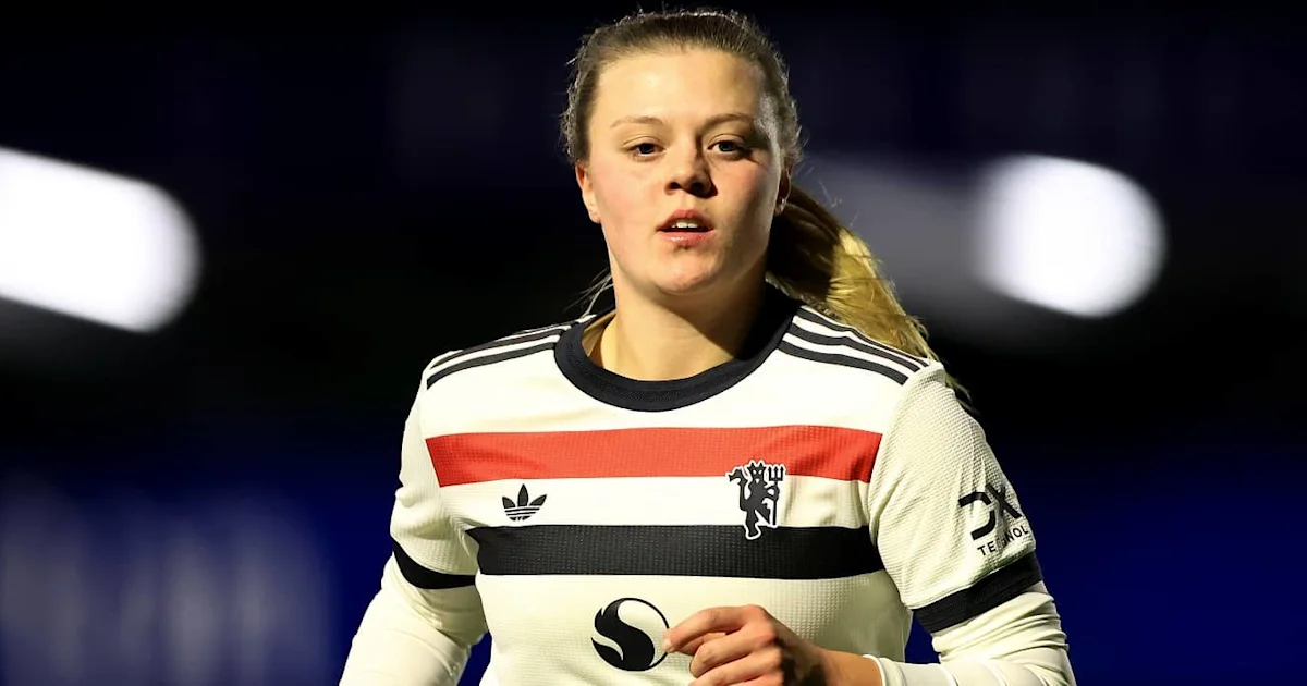 A young woman footballer in a white, red and black striped jersey runs under stadium lights.
