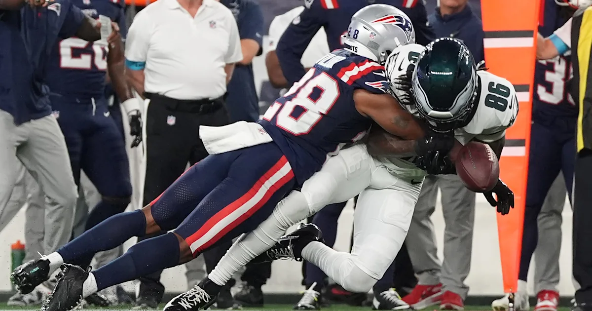 A Patriots player tackles a Bills ball carrier as the football falls near the sideline.