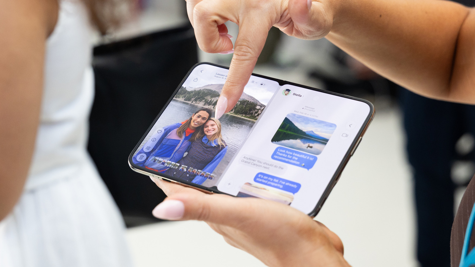 A person points at a photo on a foldable phone while holding it open to a messaging screen.