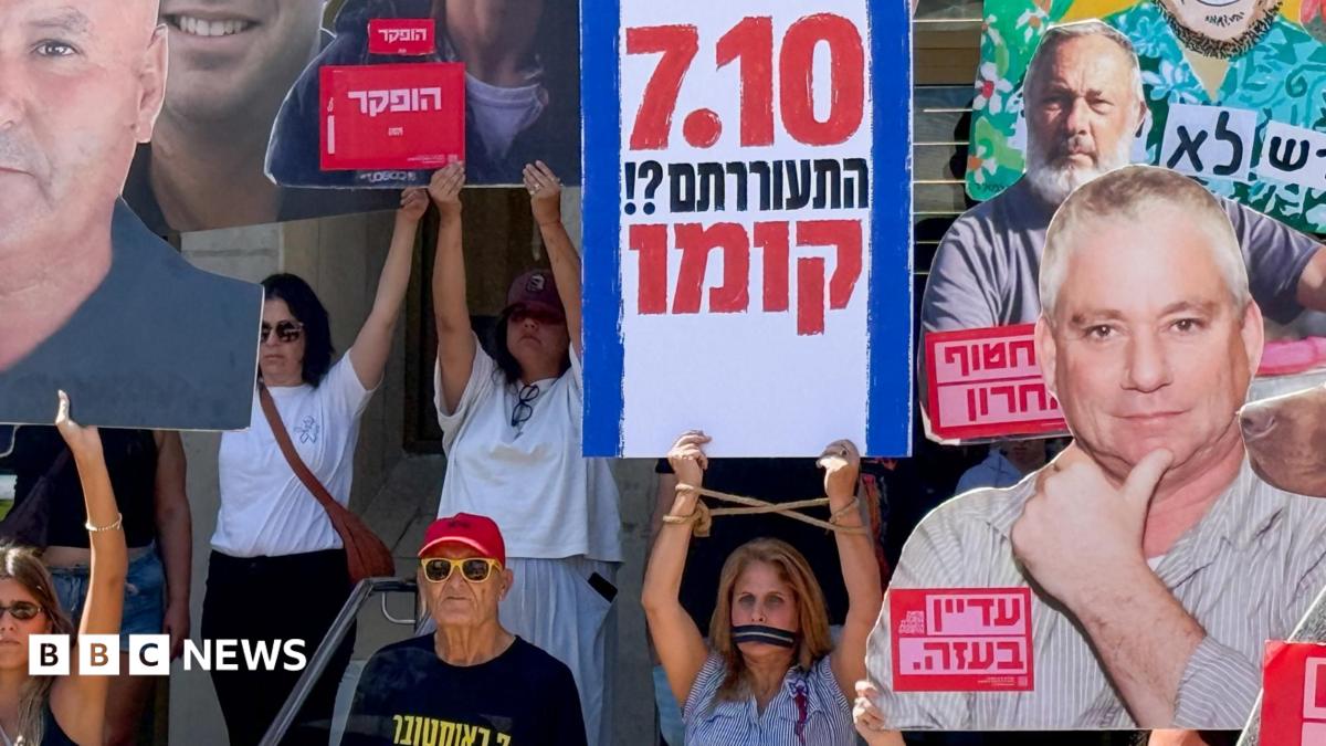 Demonstrators hold signs and large cutouts, including a prominent Hebrew placard reading “710.”