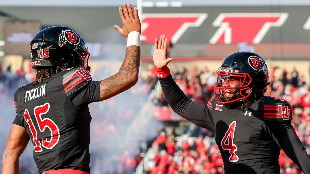 Two Utah players in black uniforms raise their hands for a high five during a game.