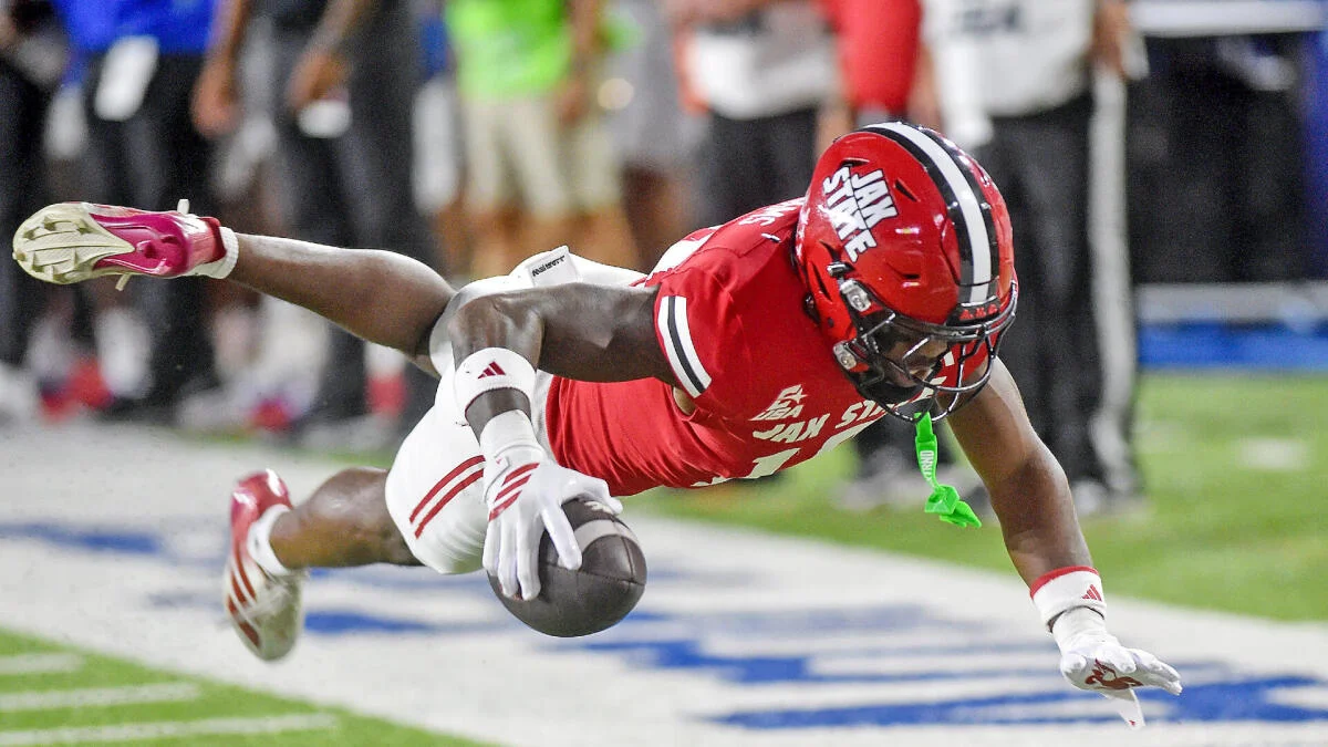 A Jacksonville State player dives forward with the football during a game.