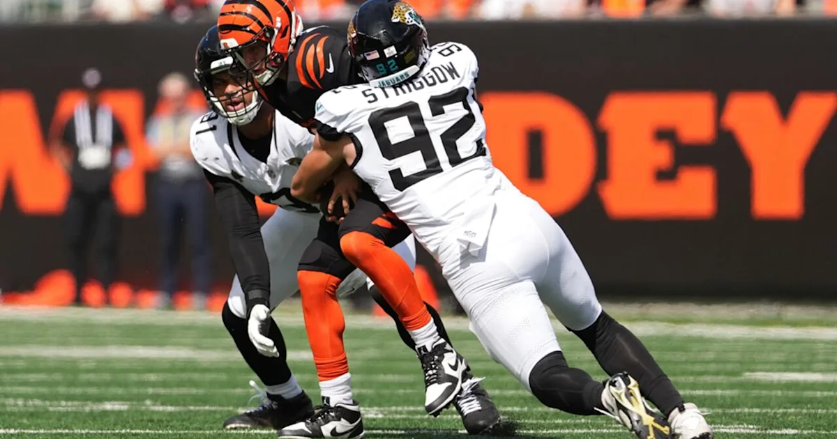 A Jaguars defender tackles a Bengals player on the field during a football game.