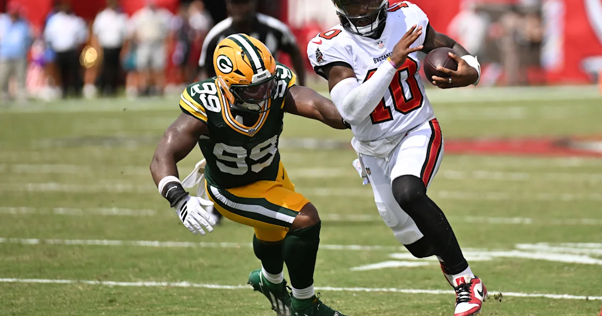 A Green Bay Packers defender reaches toward a Tampa Bay Buccaneers quarterback carrying the football.