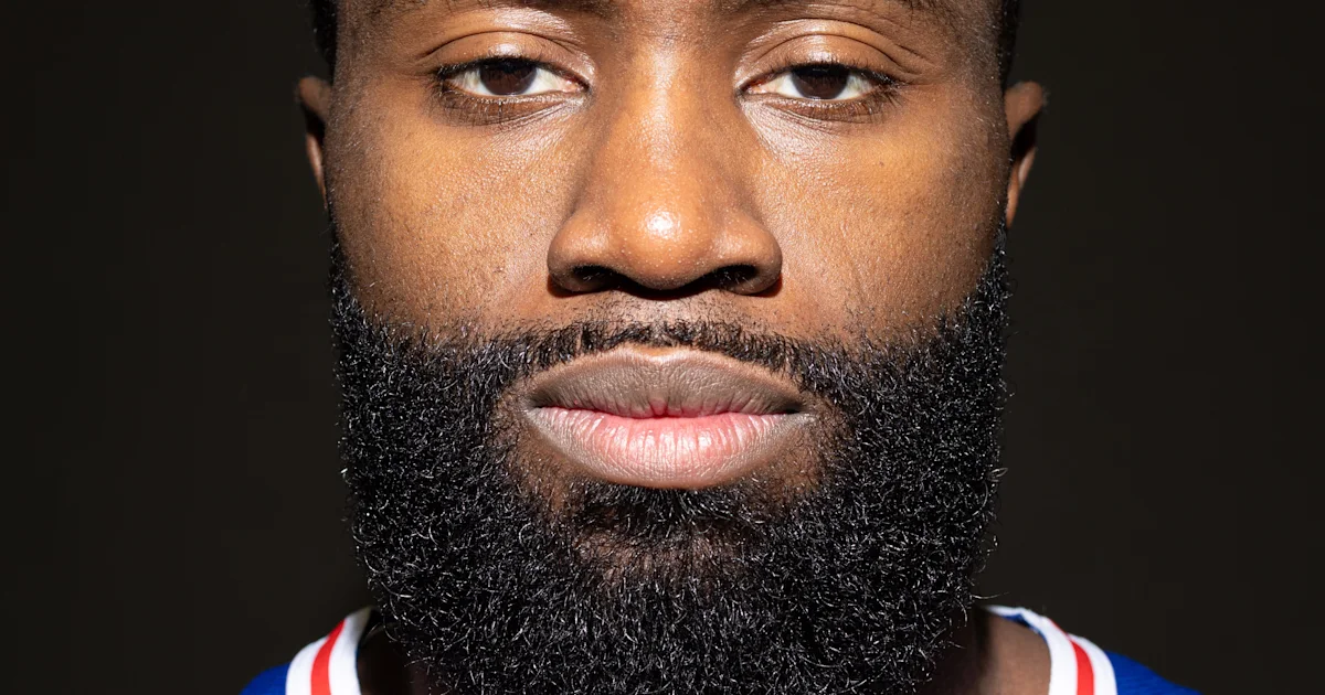 Close-up portrait of a bearded man wearing a blue jersey with red and white trim.