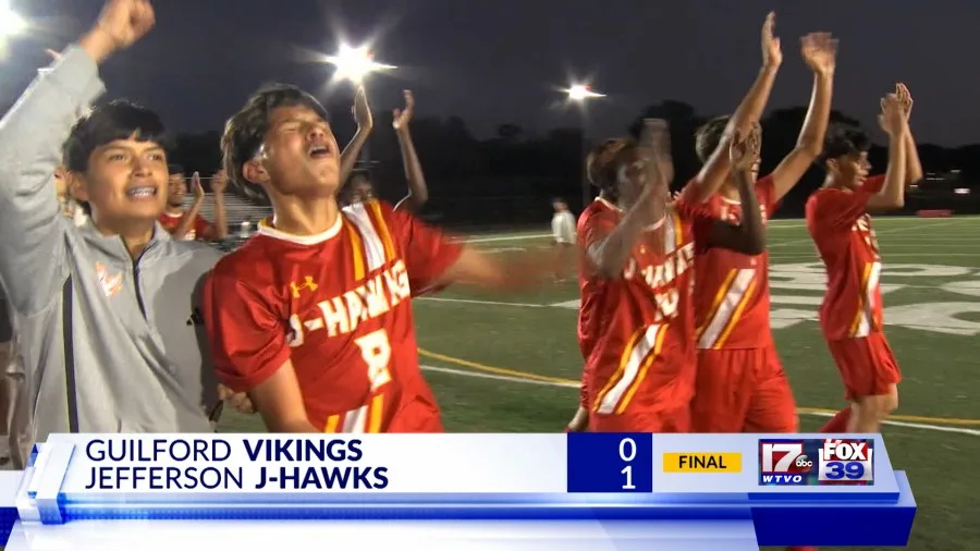 Soccer players in red uniforms celebrate on a field under stadium lights after a game.