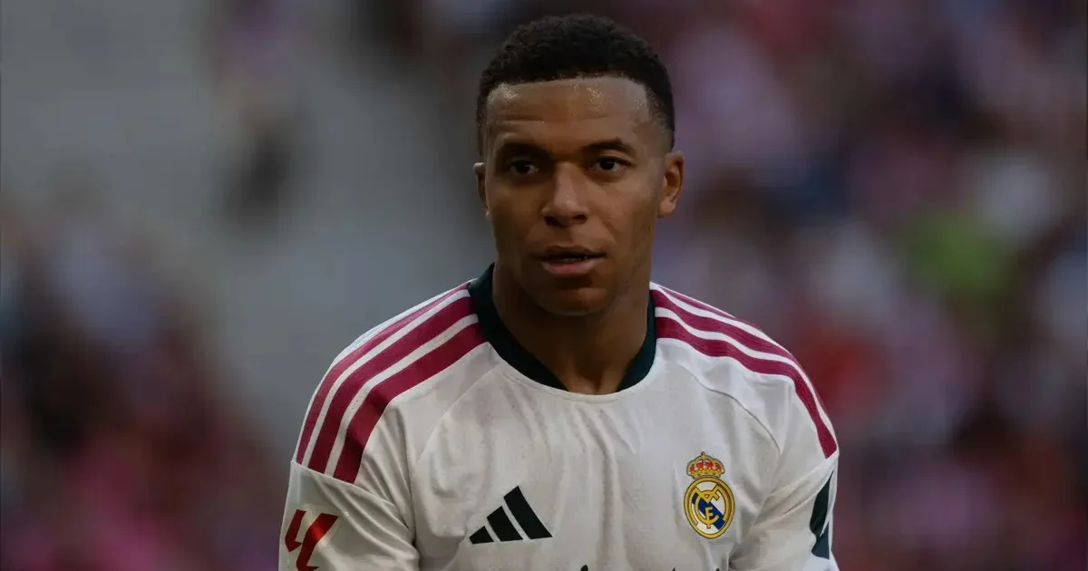 Footballer in a white Real Madrid jersey with burgundy shoulder stripes, shown from the chest up on the field.