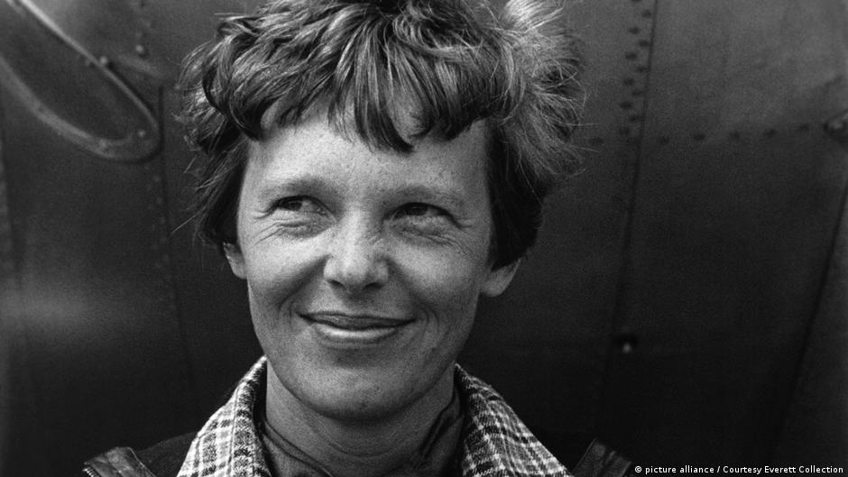 Black-and-white close-up portrait of a woman with short wavy hair, wearing a checked coat.