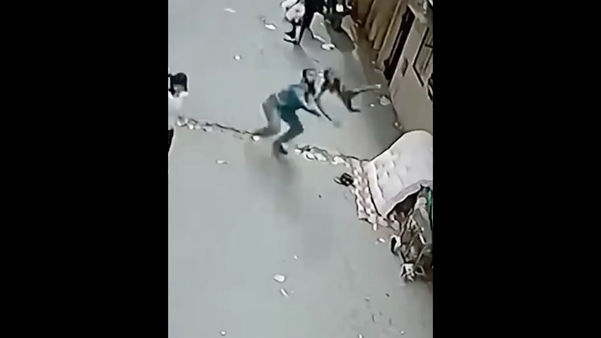 A man reaches toward a child amid scattered debris in a grainy overhead surveillance image.