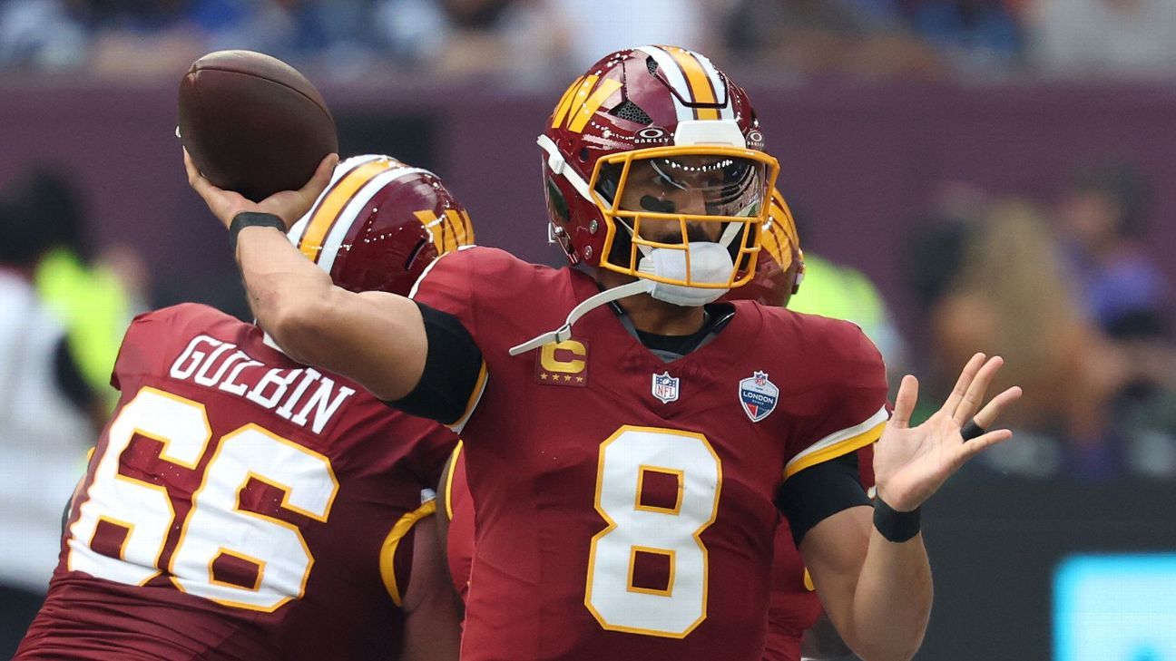 A Washington player in a burgundy number 8 jersey throws a football as a teammate stands behind him.