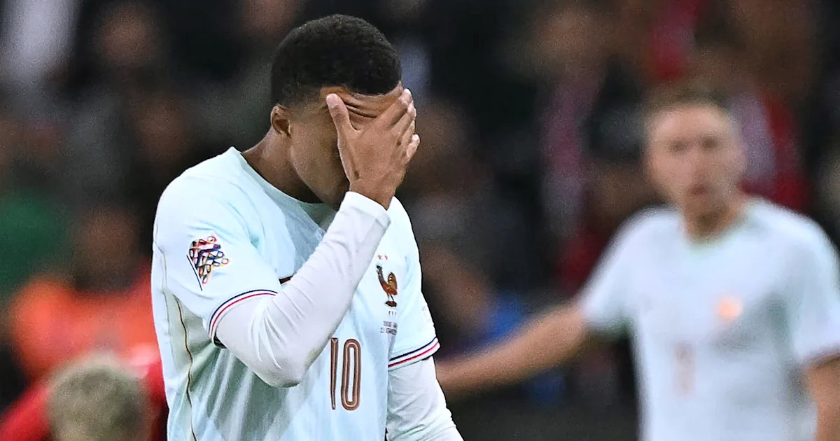 A footballer in a white number 10 jersey covers his face on the pitch.