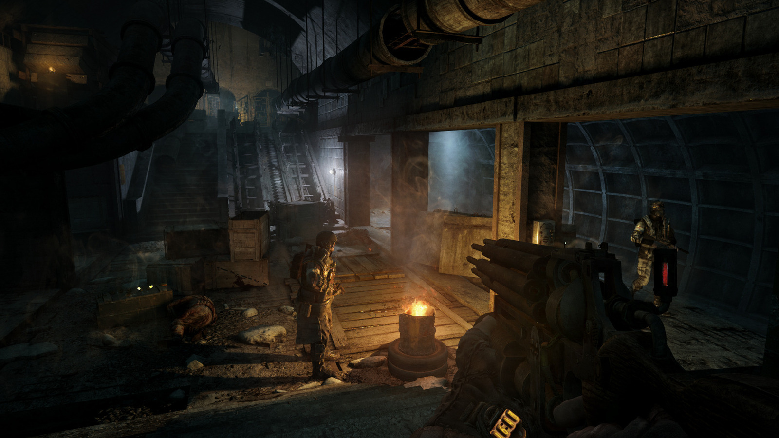 A first-person view of armed figures in a dim underground station, lit by a small fire.