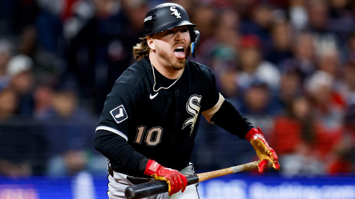 Chicago White Sox player in a black uniform shouts while holding a bat during a game.