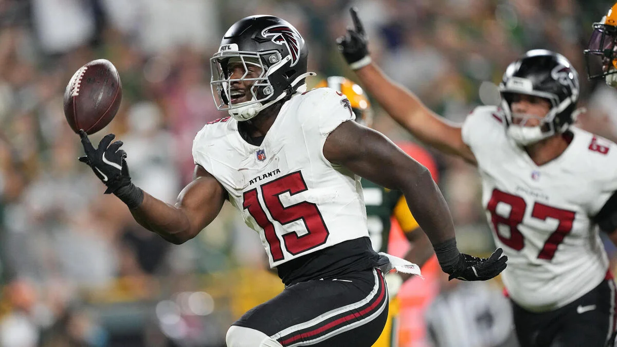 Atlanta Falcons player in a white number 15 jersey reaches toward a football during a game.