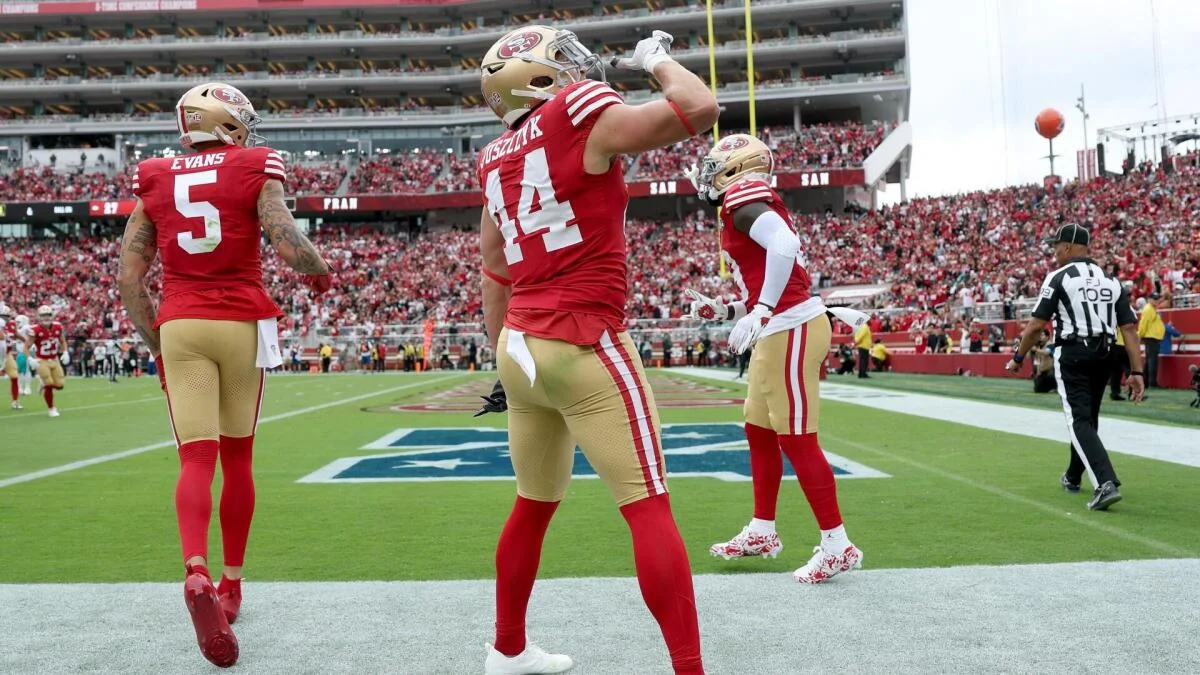 San Francisco players celebrate on the field as a teammate raises his arms near the end zone.